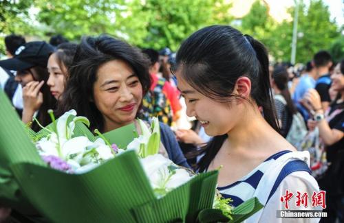資料圖：山東濟(jì)南眾多考生手捧鮮花在家長的簇?fù)硐職g快告別高考。中新社記者 張勇 攝