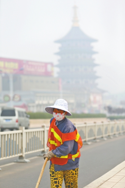 近日，在古都洛陽(yáng)，環(huán)衛(wèi)工人身后的“天堂”被霧霾籠罩著。
