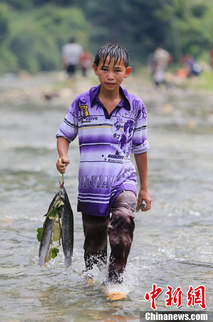 圖為7月9日，一名男孩在鬧魚節(jié)活動中抓到了兩條魚。譚凱興 攝