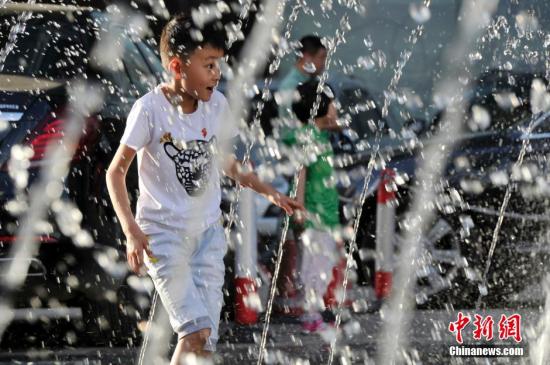 山西太原最高溫36℃,兒童在噴泉周圍戲水消暑。
