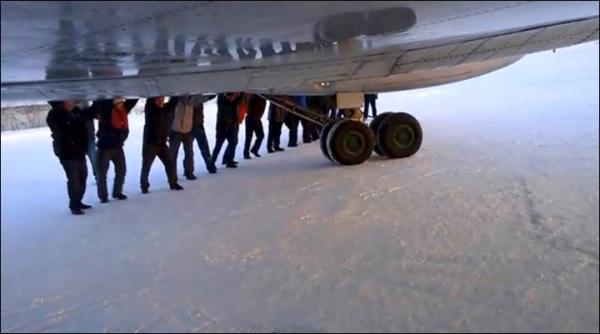 　伊加爾市一架客機起飛前被凍在了跑道上。飛機上的乘客不得不下來推飛機。