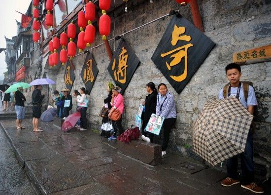 　4月29日上午11時20分，一些游客和古城當?shù)氐木用穸阍谝粋€酒吧的屋檐下避雨。這些當?shù)鼐用褚詾橛慰团恼罩\生，一場降雨讓他們的生意更加清淡。
