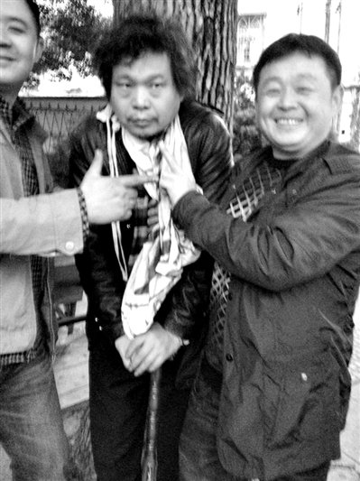 兩名接訪人員與患有癌癥的訪民段新德合影時(shí)，面帶笑容擺出勝利的手勢(shì)。