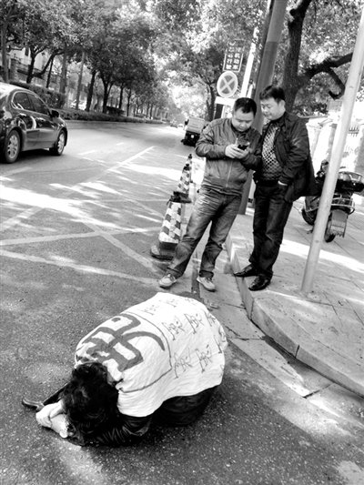 兩名接訪人員與患有癌癥的訪民段新德合影時(shí)，在拍照時(shí)查看手機(jī)。