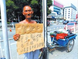 老人舉著牌子在路邊等候失主。京華時報記者譚青攝