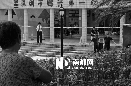 →7月19日，鵬興花園第一幼兒園門前，民警在現(xiàn)場進行完勘查取證后，園長和保安的尸體被運走。南都記者 徐文閣 攝