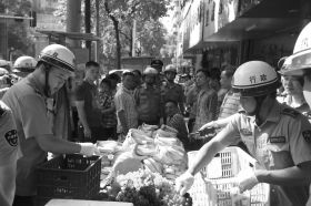 7月11日，瀏陽市北正中路，執(zhí)法人員暫扣張海的水果。這是瀏陽市城管局拍攝的執(zhí)法現(xiàn)場圖。