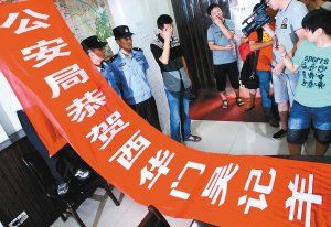 面對警方收繳的條幅，老板楊某也不好意思地用手遮擋臉