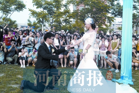 在學(xué)校操場的草坪上，兩名畢業(yè)生舉行婚禮，有同學(xué)感動地抹起眼淚