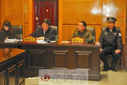 庭審現(xiàn)場，被告人坐在律師身旁為自己辯護(hù)。