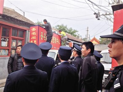 昨日下午,東城區(qū)工商、城管、公安等部門,對(duì)雍和宮附近的預(yù)測(cè)中心進(jìn)行清理整頓,站在車頂?shù)膬擅と苏鸪患摇邦A(yù)測(cè)中心”的招牌。因雍和宮、白云觀等文化景點(diǎn)外聚集大量算命先生,被媒體稱為“算命一條街”。本版攝影/新京報(bào)記者 李寧 攝