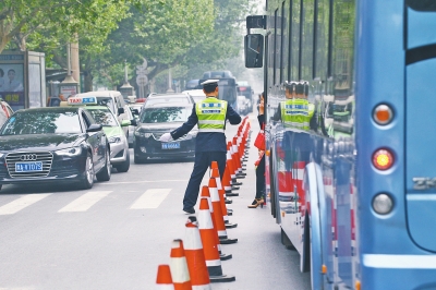 省人民醫(yī)院南門的路中間擺放反光錐，交警示意由西向東車輛從前方繞行。