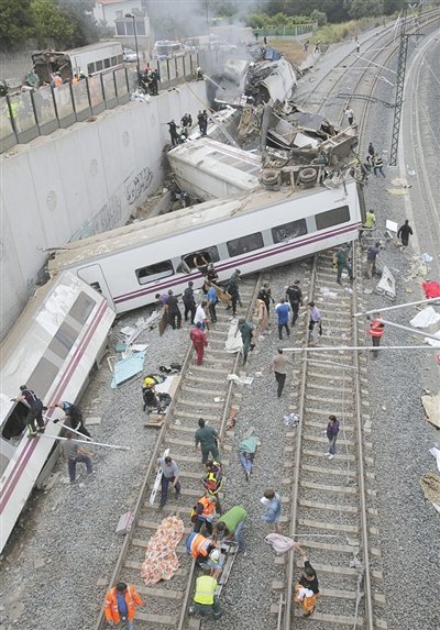 24日，救援人員在西班牙列車脫軌現(xiàn)場(chǎng)。一節(jié)車廂被強(qiáng)大的慣性拋上鐵道邊的高臺(tái)。