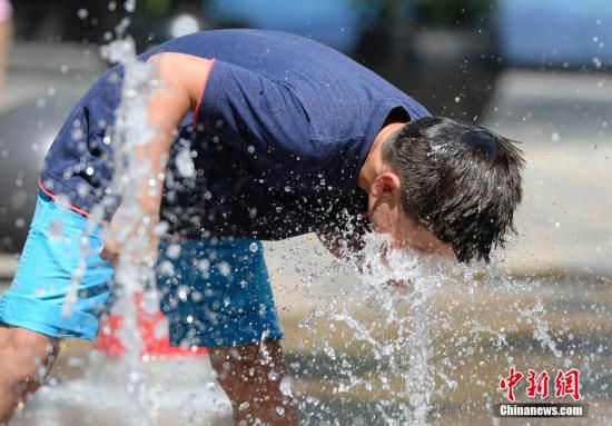 5月29日，一名小孩將頭伸向北京街頭的噴泉以降溫祛暑。