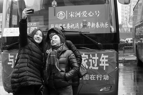 昨天上午8時，鄭州正道中環(huán)百貨廣場，準備回家的老鄉(xiāng)在愛心大巴車前合影留念