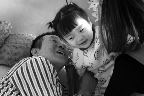 病床前李剛父女倆說著“悄悄話”，幸福的氣氛洋溢在病房中