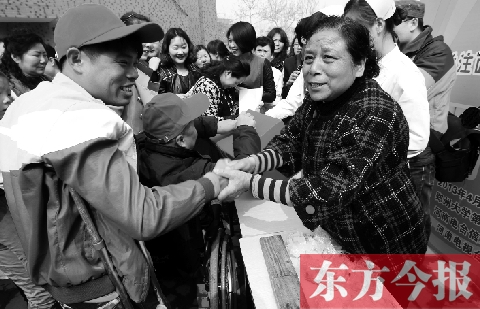 昨日，鄭大四附院的大樓前，“面人鄭”鄭玉芬（右）向前來捐款的殘疾人表示感謝