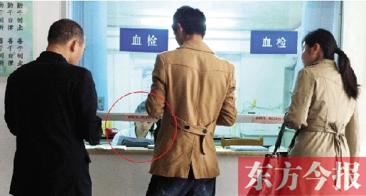 昨日，鄭州市二七區(qū)疾控中心辦證大廳，血檢窗口內(nèi)一名女工作人員，邊接受辦證者咨詢邊看報紙