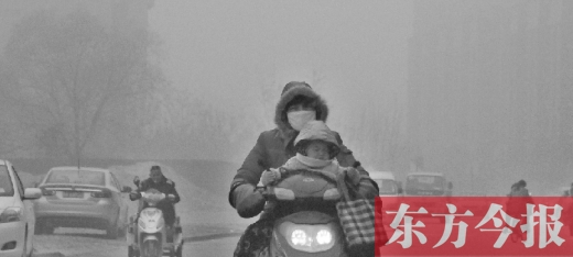 12月8日，鄭州市未來(lái)路上，一位市民帶著孩子在霧中騎行