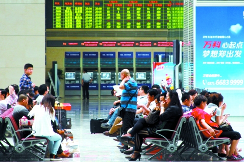候車大廳溫度很高，一名乘客一手扇風(fēng)、一手擦汗