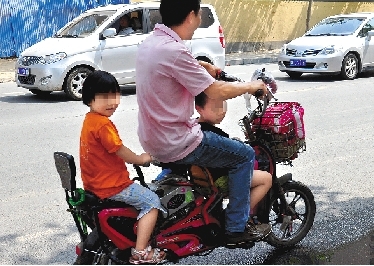 周先生騎著一輛低矮的電動(dòng)車帶著一對(duì)兒女，很不安全。