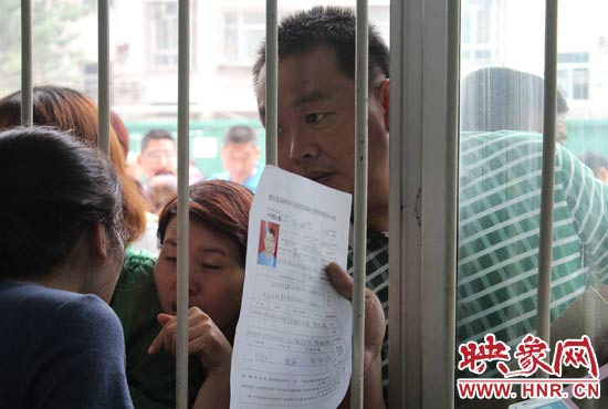 不少家長(zhǎng)擠在報(bào)名窗口前咨詢報(bào)名事宜。
