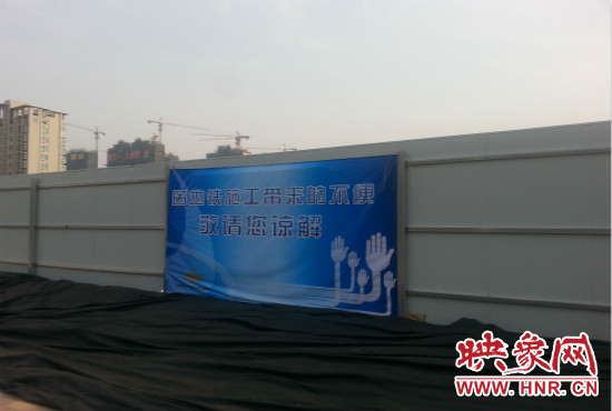 道路南側(cè)圍起了白色的圍擋，墻上標(biāo)示著“因地鐵施工帶來(lái)的不便敬請(qǐng)您諒解”的提示牌。