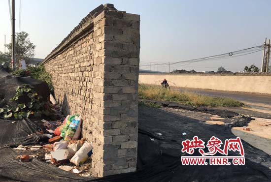 一墻之隔，一邊是道路，一邊是垃圾和荒草，市民質(zhì)疑其為遮羞墻。