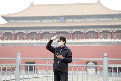 11月1日，北京大部分地區(qū)重度污染，一名游客戴著口罩在午門前揮手跟朋友打招呼。 實習生 王飛 攝