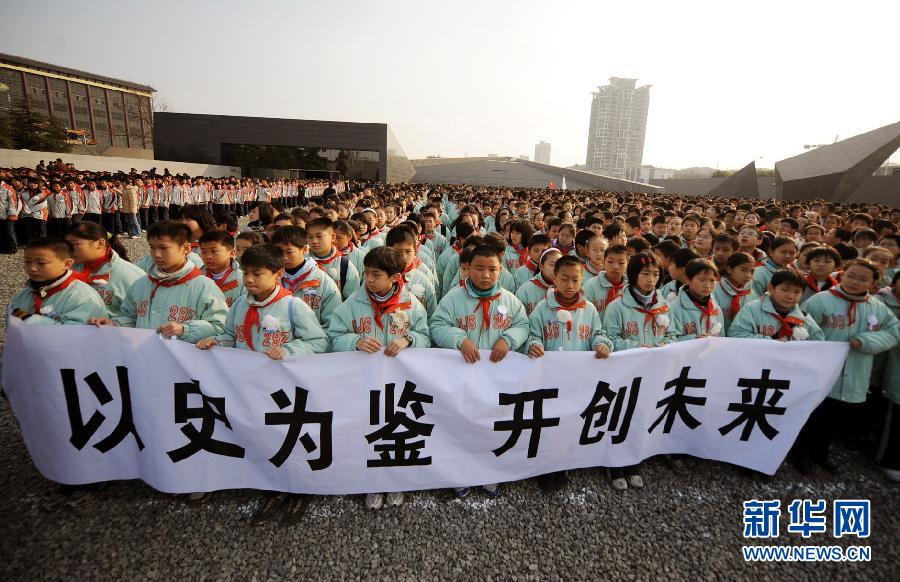 ，南京市小學(xué)生代表手持“以史為鑒 開創(chuàng)未來”的橫幅在南京大屠殺遇難同胞紀(jì)念館集會廣場參加悼念儀式。　