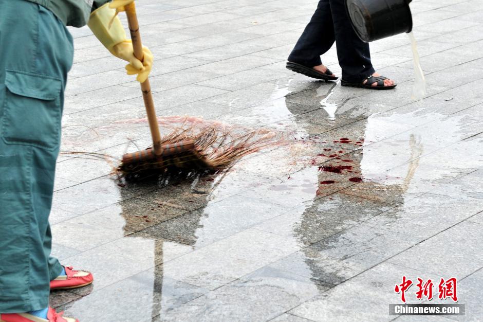 圖為環(huán)衛(wèi)工人在清理案發(fā)地點的血跡。