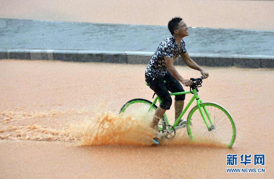 5月11日，一名行人在深圳街頭冒雨騎行。