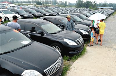 昨日，市民在山東棗莊一家拍賣公司場地上查看待拍賣公車。當日，棗莊市103輛公車公開拍賣。新華社記者