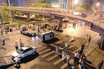 路虎沖下國(guó)貿(mào)橋砸中一輛起亞轎車(chē)，橋上厚達(dá)幾十厘米的水泥護(hù)欄被撞斷，碎石四處散落，數(shù)十群眾在現(xiàn)場(chǎng)圍觀。