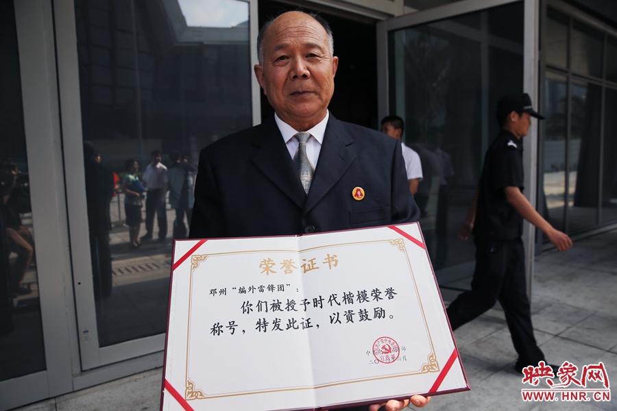 河南鄧州“編外雷鋒團(tuán)”團(tuán)長宋清梅向眾多記者展示中宣部授予的“時代楷?！睒s譽(yù)證書。