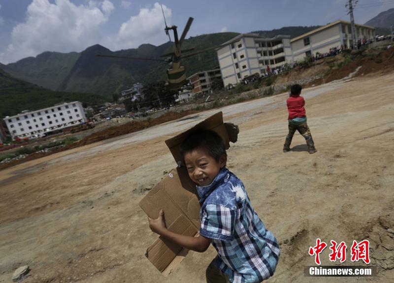 云南省昭通市魯?shù)榭h發(fā)生6.5級地震。幾個孩子在直升機降落的平地上玩耍。