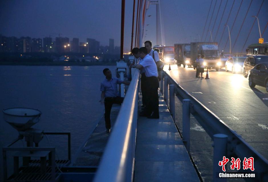 圖為武漢警方談判專(zhuān)家正在與翻爬至大橋外側(cè)護(hù)欄的劫持者談判。