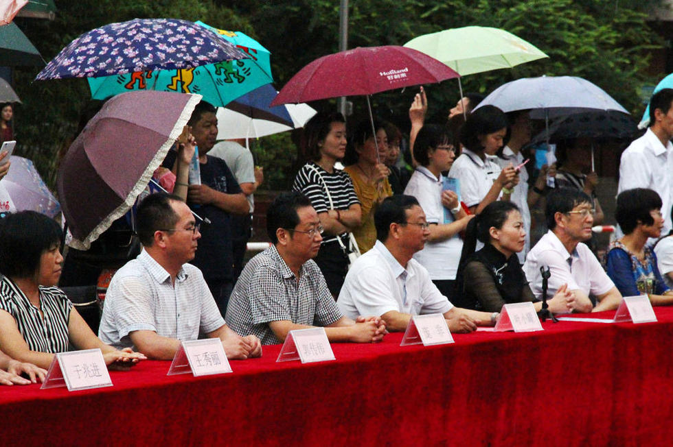 在主席臺上觀看的校領導也堅持不打傘陪學生一起淋雨，身旁站滿了打傘觀看的家長。