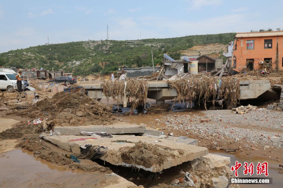 圖為洪水過(guò)后，坍塌的橋梁上遺落大量雜草。