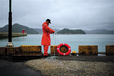 7月6日，韓國珍島，一名海岸警察在港口系救生圈。4月，客輪在珍島近海發(fā)生沉船事故后，仍有11人下落不明。