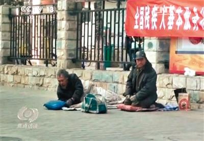 工人體育場(chǎng)北路，兩位乞討者路邊乞討，并輪流扮成“病人”（躺地者）。 央視截圖