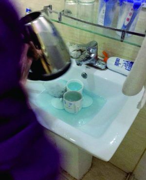 酒店服務(wù)員用潔廁液刷燒水壺和茶杯。