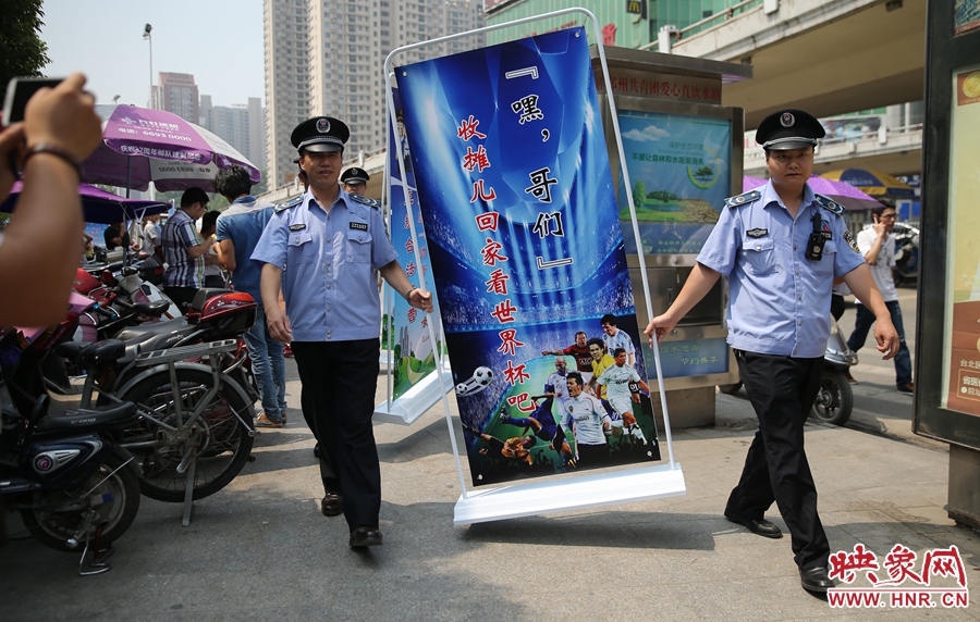 7月2日上午，鄭州市紫荊山地鐵站出入口，執(zhí)法人員抬著寫有勸導(dǎo)語的宣傳板，前往占道經(jīng)營攤位“圍觀執(zhí)法”