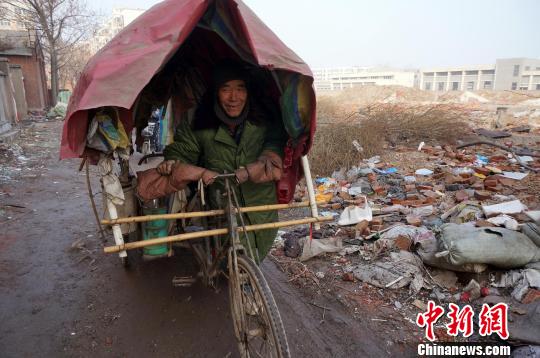 圖為老人走出窩棚，推著三輪車準(zhǔn)備出去撿拾廢品。周小云 攝